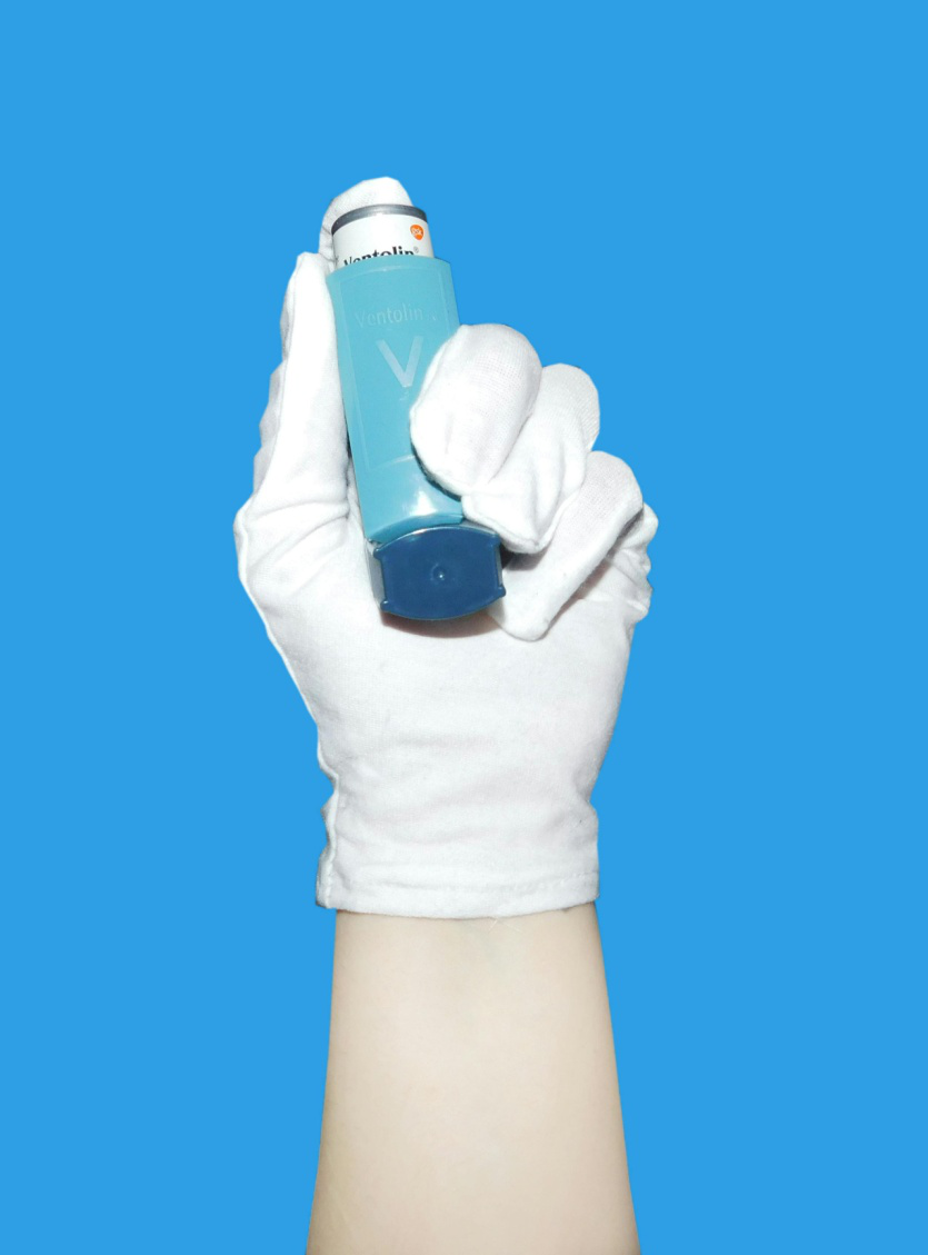 a person wearing a glove holding an inhaler  