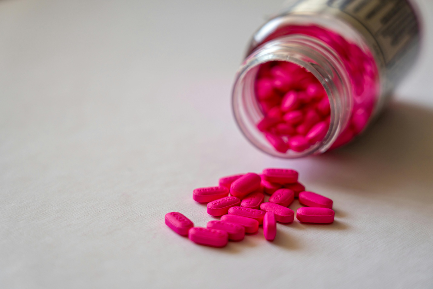 A close-up of an open prescription medication bottle with scattered pills