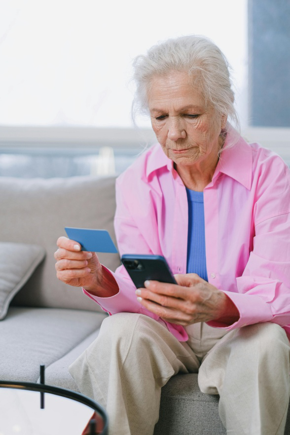 An elderly woman holding a prescription assistance card