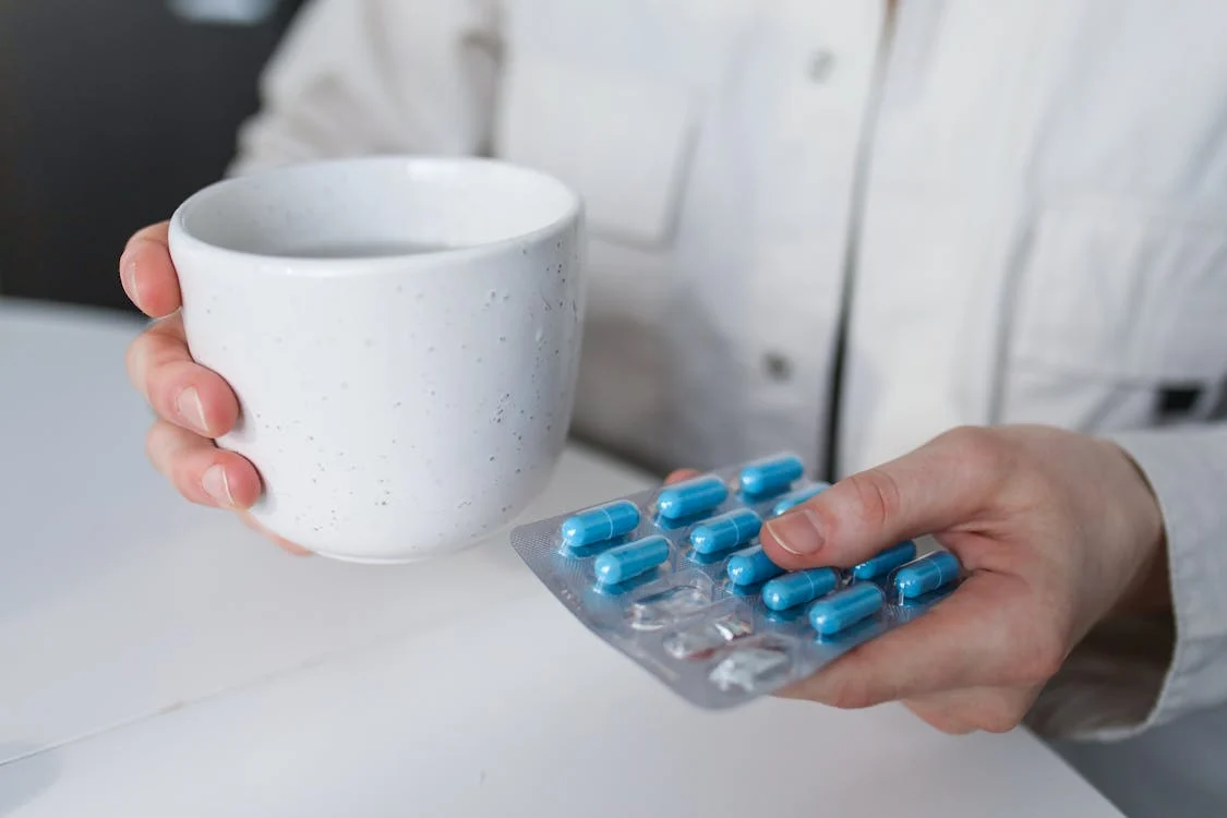 Person holding medicine and a cup of water