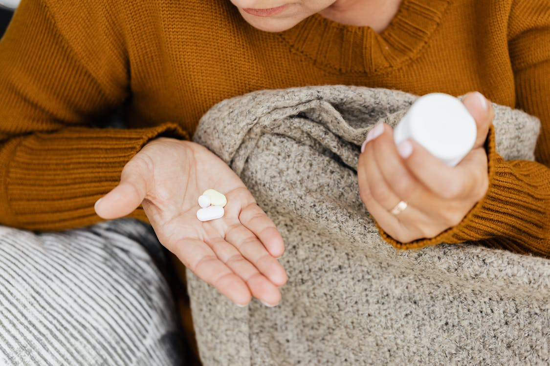 A close-up shot of a person holding a bottle of medication in their hand.