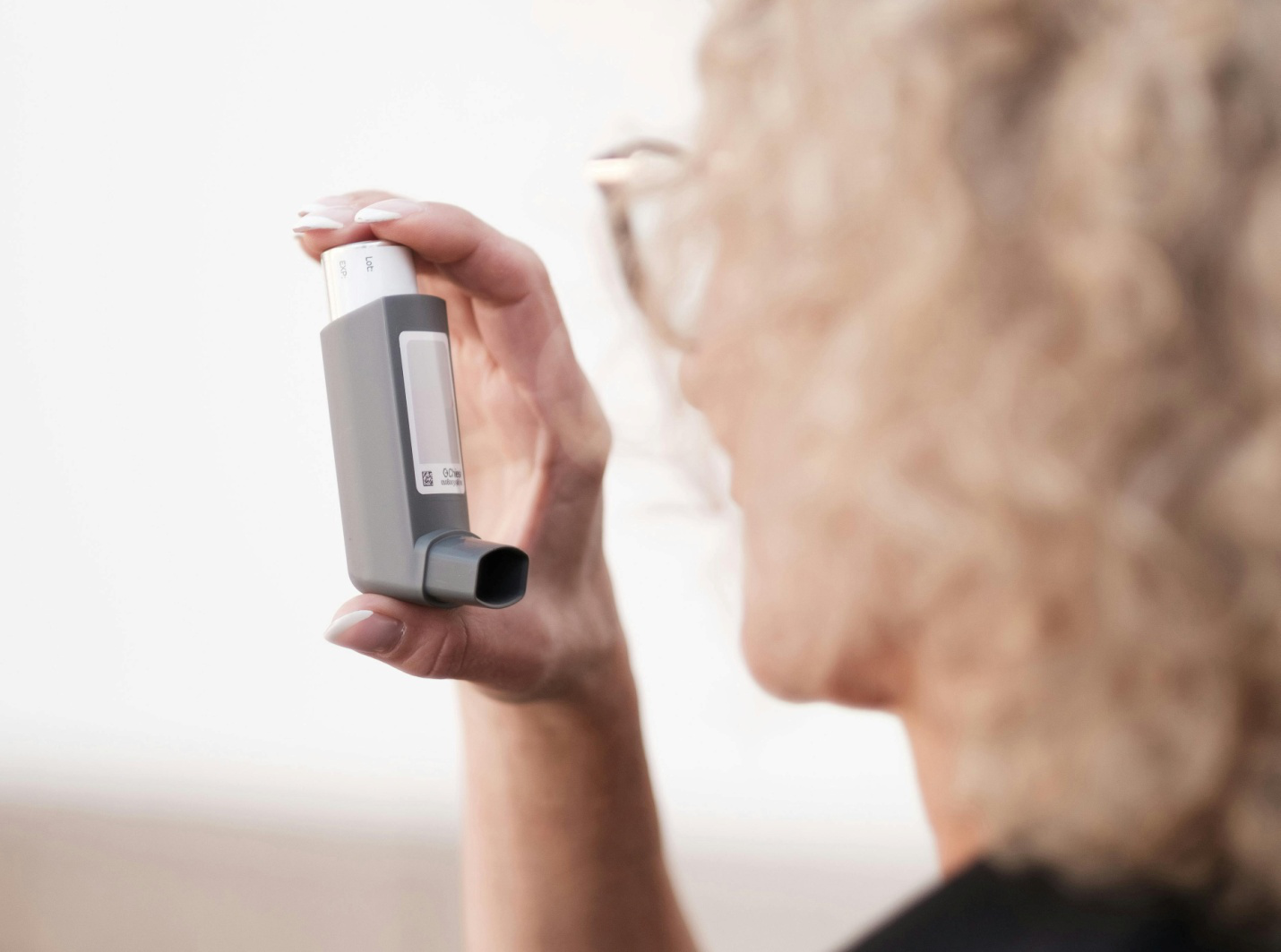 a woman holding up a grey inhaler
