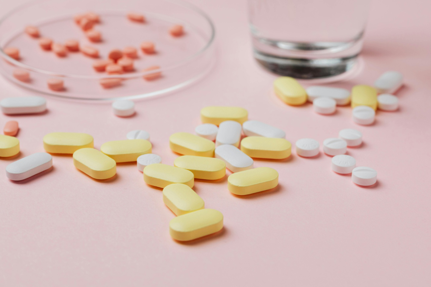 yellow and white medicines spread out on a pink surface