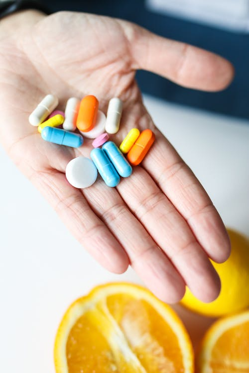 Hand holding several multi-colored pills, symbolizing diverse prescription needs.