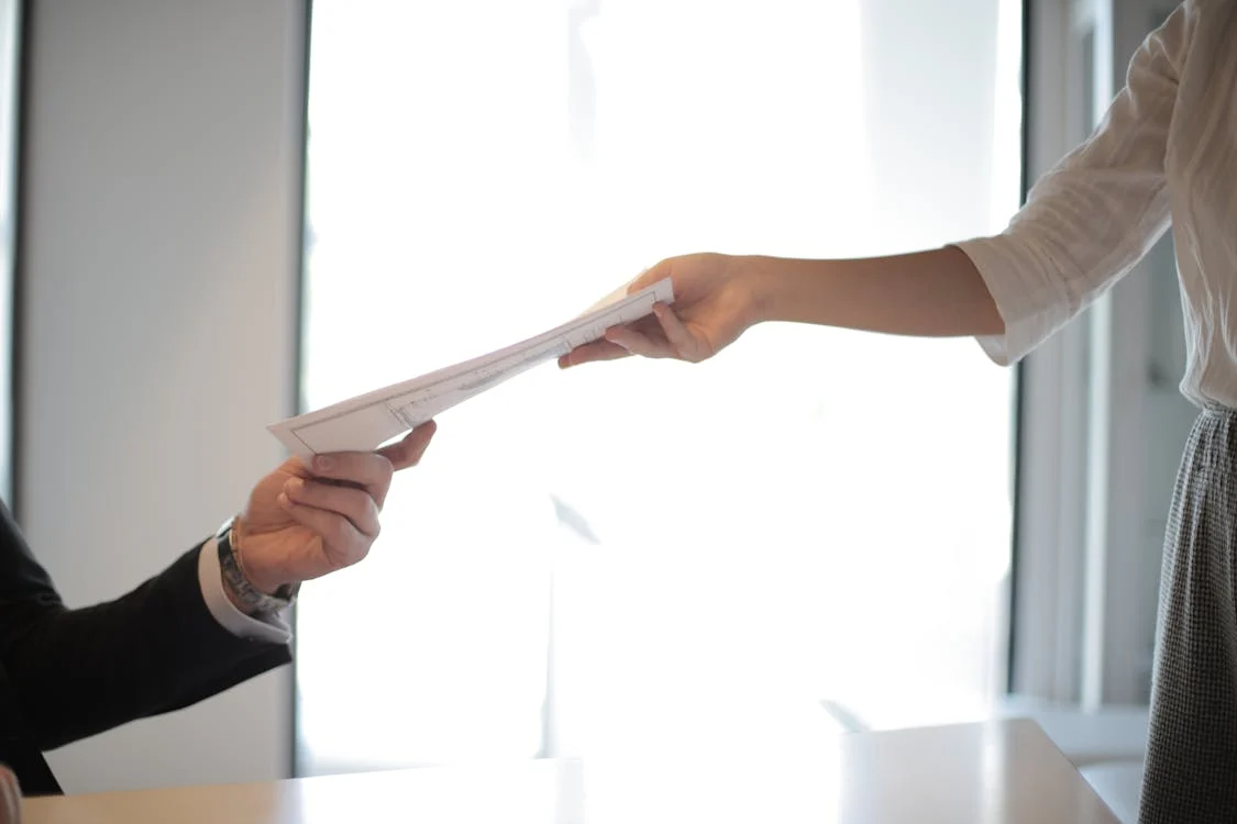 Person handing documents to another person