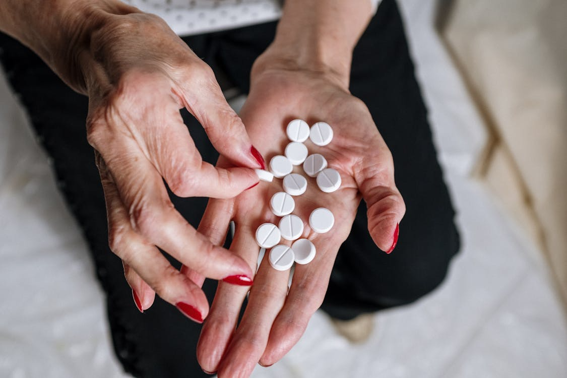 Elderly person holding white pills in her hands