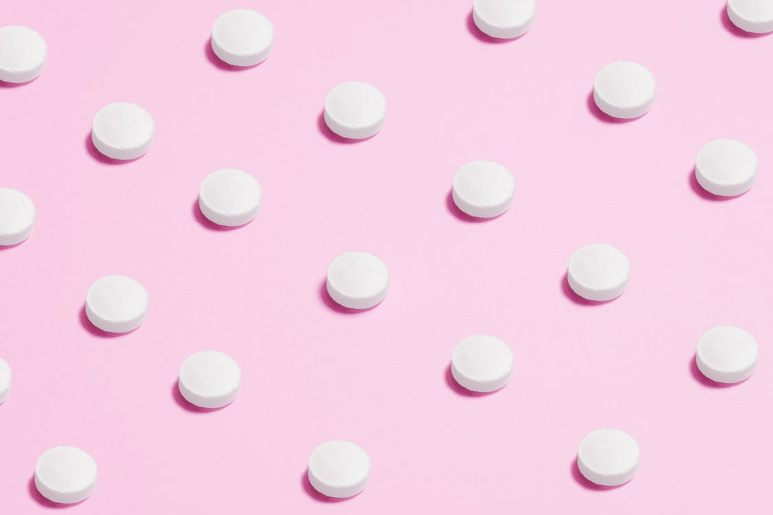 White pills on a pink background