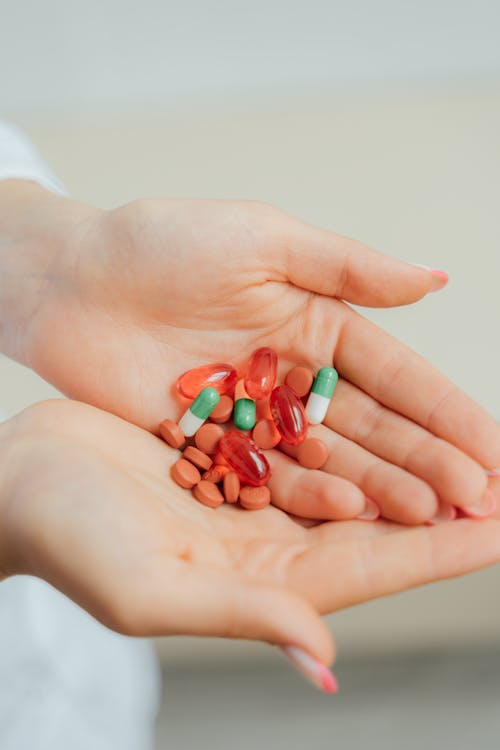 Hands holding a mix of capsules and tablets