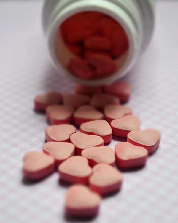 Heart-shaped tablets spilled from a medication bottle