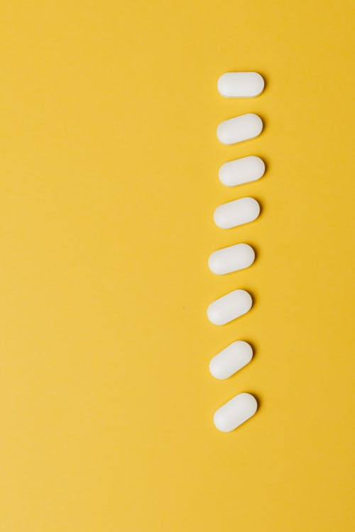White tablets arranged in a vertical line on a yellow background