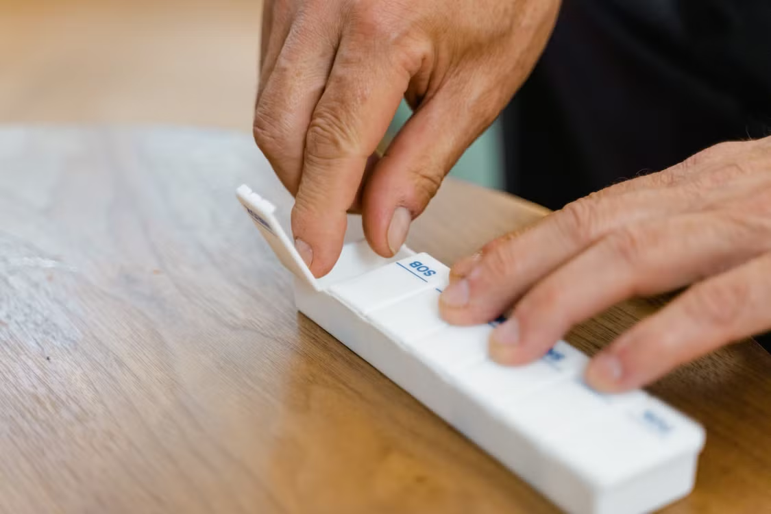 A person holding a white medication box while reviewing prescription information.