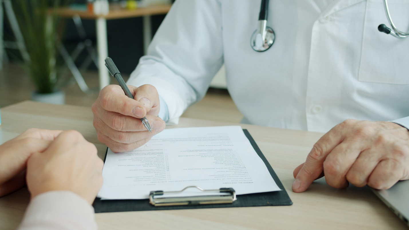 Doctor writing a prescription on a notepad during patient consultation