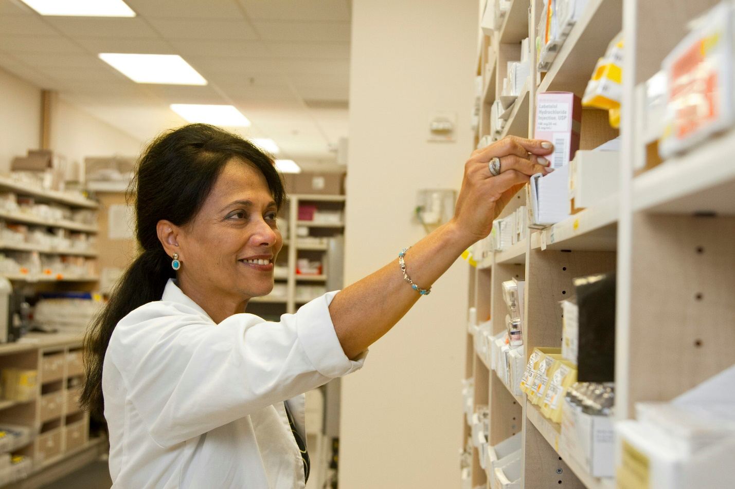 Pharmacist organizing and dispensing medicines behind pharmacy counter