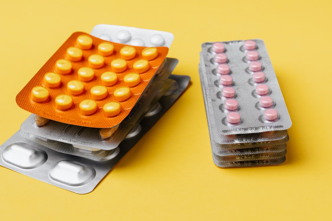 Blister packs of prescription medication tablets on a yellow background