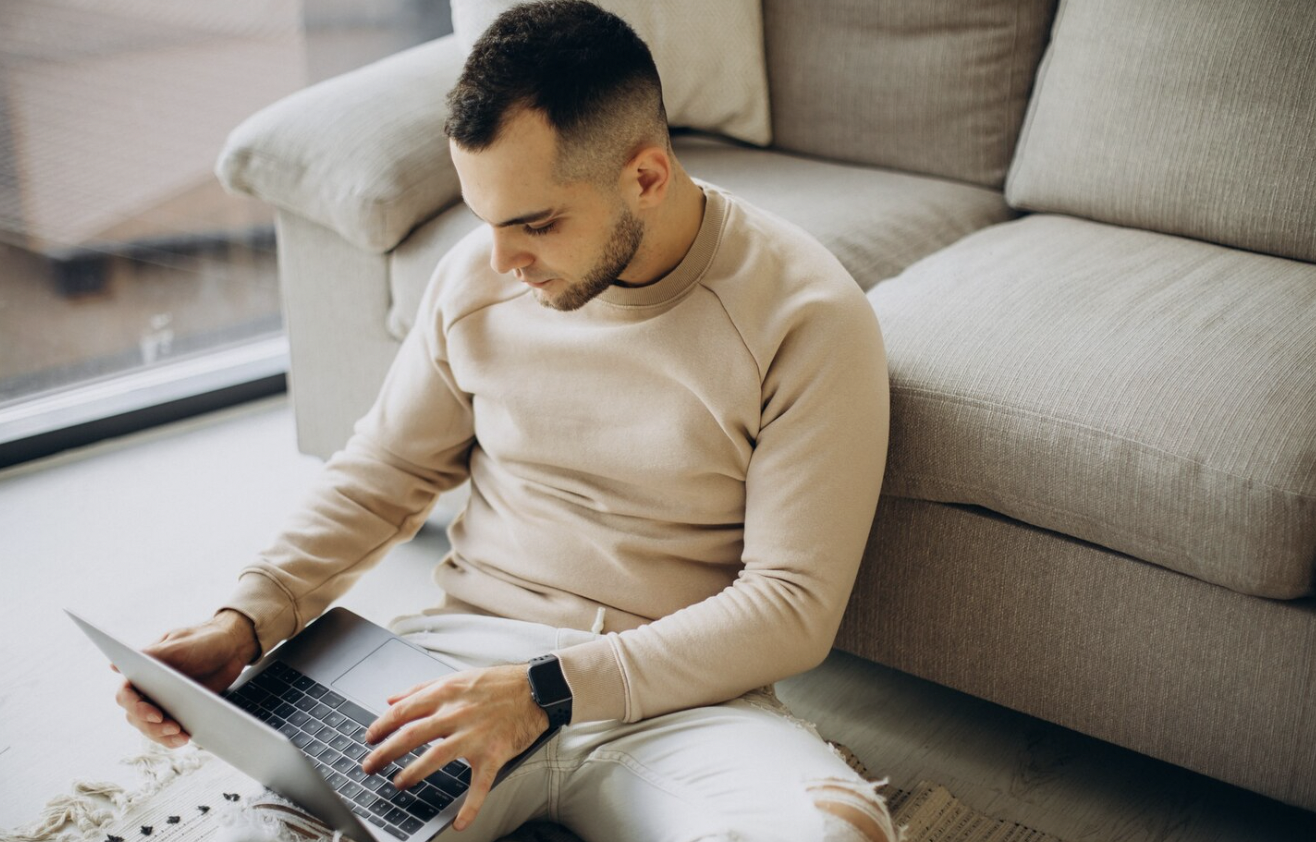 Man using a laptop at home to review prescription assistance eligibility and application information.