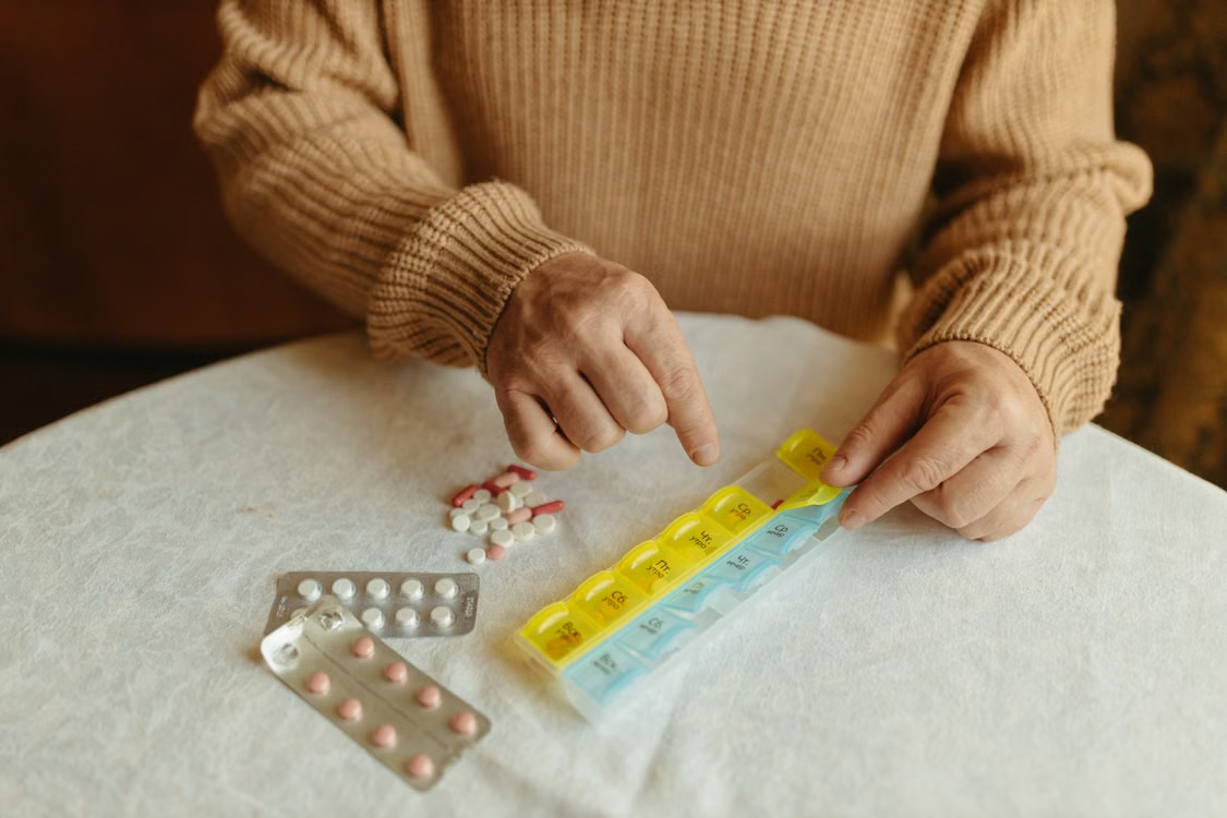 Patient organizing prescription medications in a weekly pill organizer