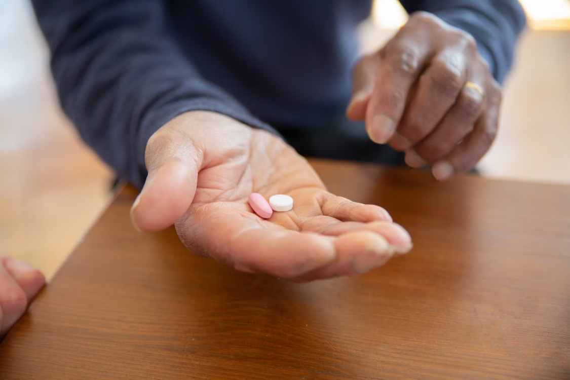 Person holding two prescription pills in their hand before taking medication.