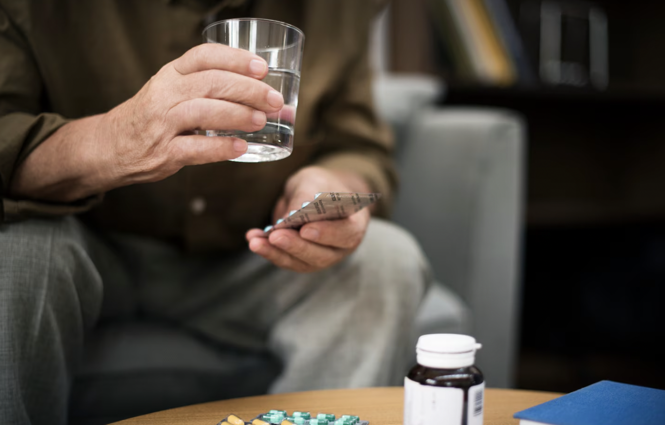 Man taking prescription medication at home while managing his ongoing treatment.