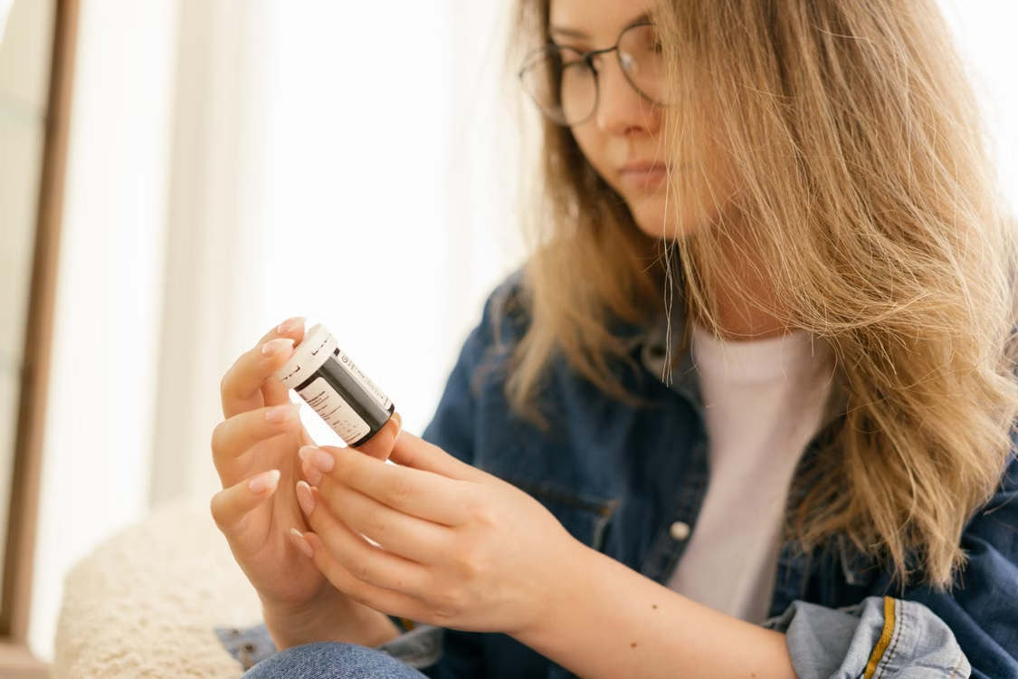 Patient reading the label on a prescription medication bottle before taking medication