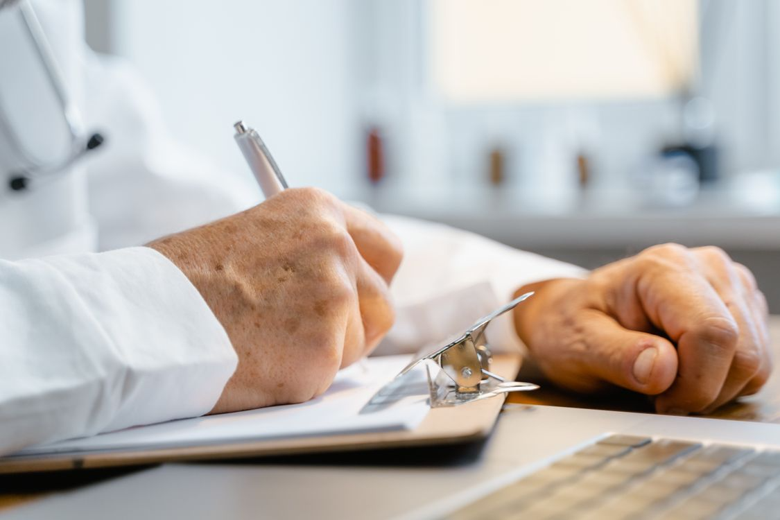 Doctor writing a prescription during a patient consultation at a medical office