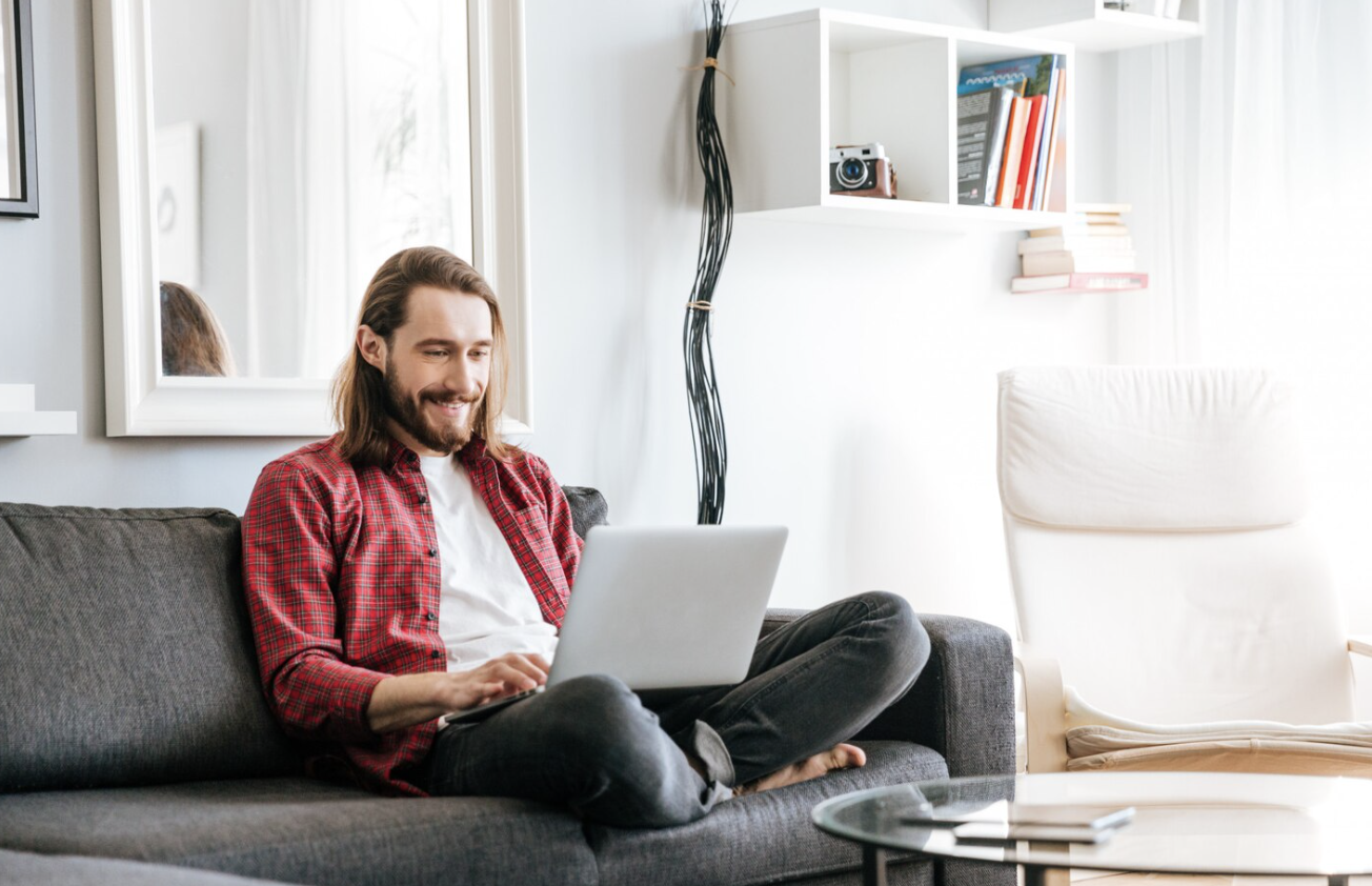 Man using a laptop at home to research patient assistance programs and prescription cost support options.