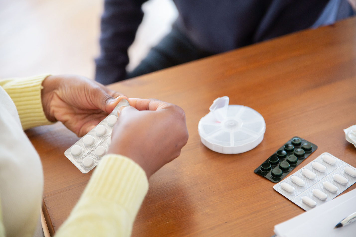 Patient reviewing prescription medications while preparing documents for medication assistance