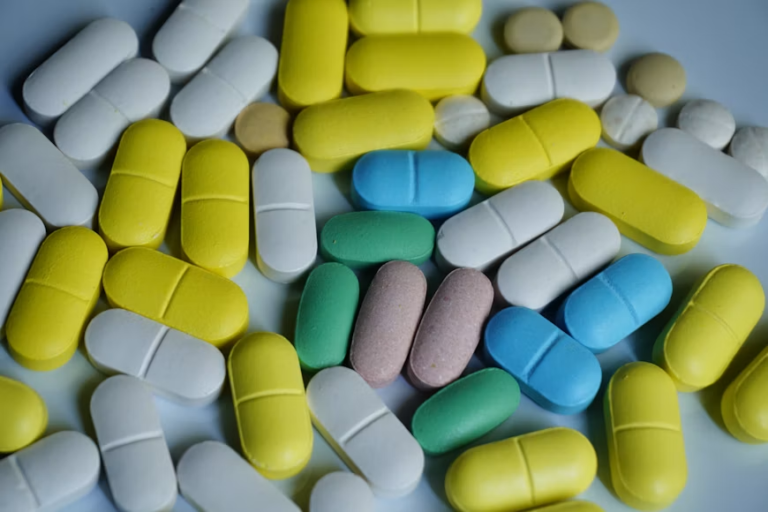 Assorted yellow, white, blue, green, and pink tablets arranged across a light-colored surface.