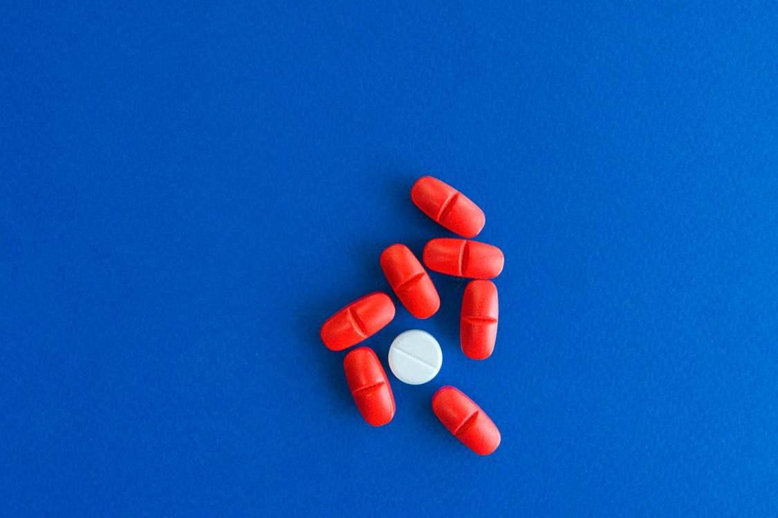 Red and white tablets arranged in a circular pattern on a bright blue background.