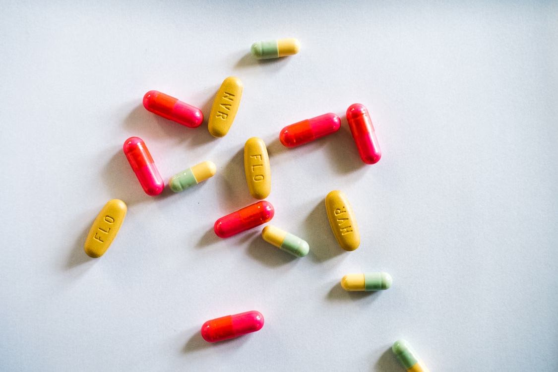 Red, yellow, and green capsules scattered across a light-colored surface.
